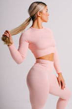 Load image into Gallery viewer, a woman stading holding her hair, wearing trueform ribbed long sleeve top and leggings of pink colour
