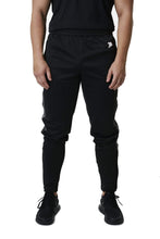 Load image into Gallery viewer, A man wearing true form black tracksuit bottoms

