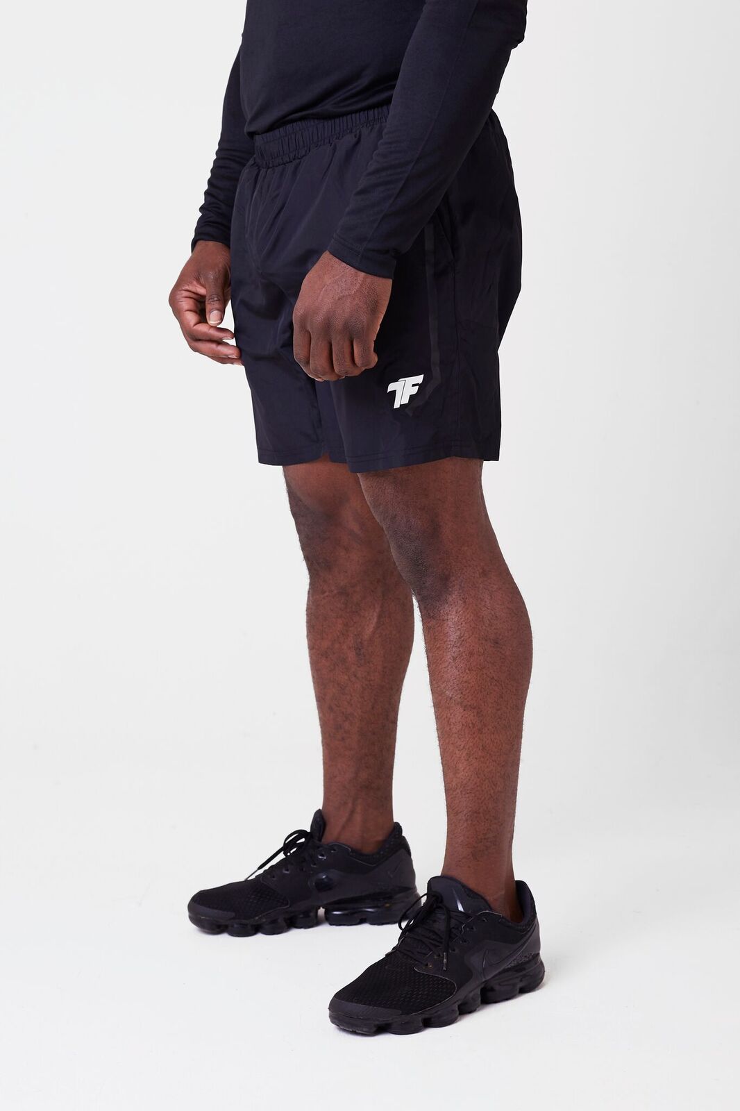 A man wearing black shoes and black true form shorts of the brand trueform uk 