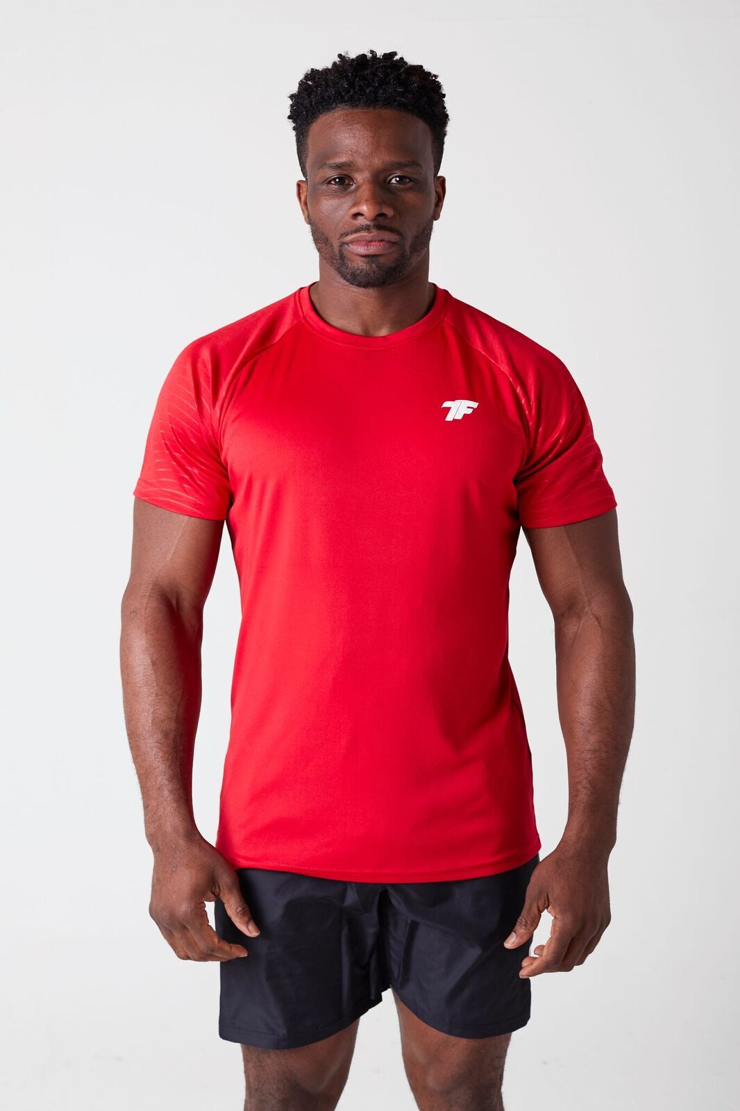 A man wearing True Form's Black Shorts and Red T-Shirt for Gym